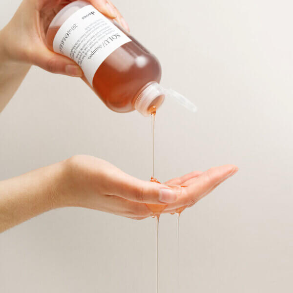 Davines Solu Shampoo being poured from bottle onto hand