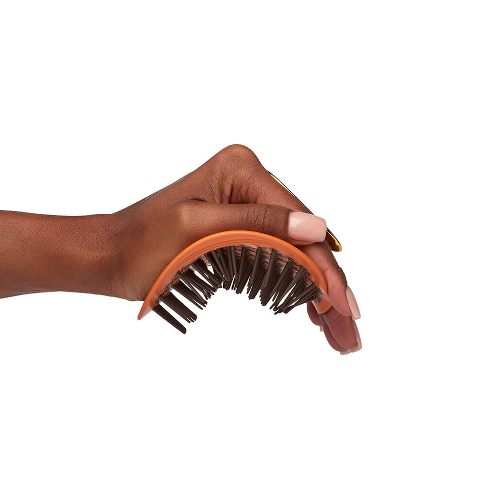Manta coily hair brush in amber orange being bent in hand
